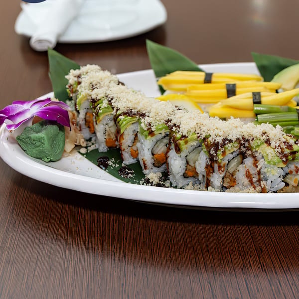Bleu Ginger's sushi roll with avocado, sauce, and crunchy topping, garnished with a purple orchid.