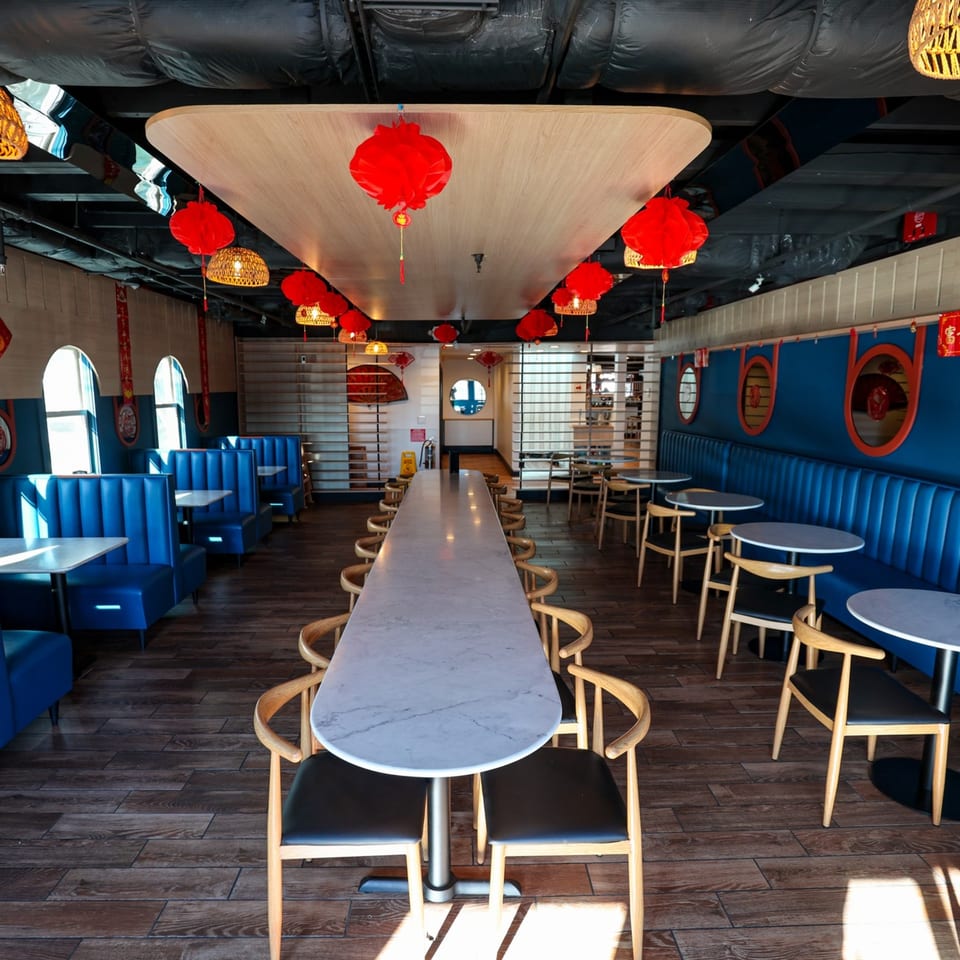Bleu Ginger's dining room with blue booths, long communal table, and red lanterns hanging from the ceiling.