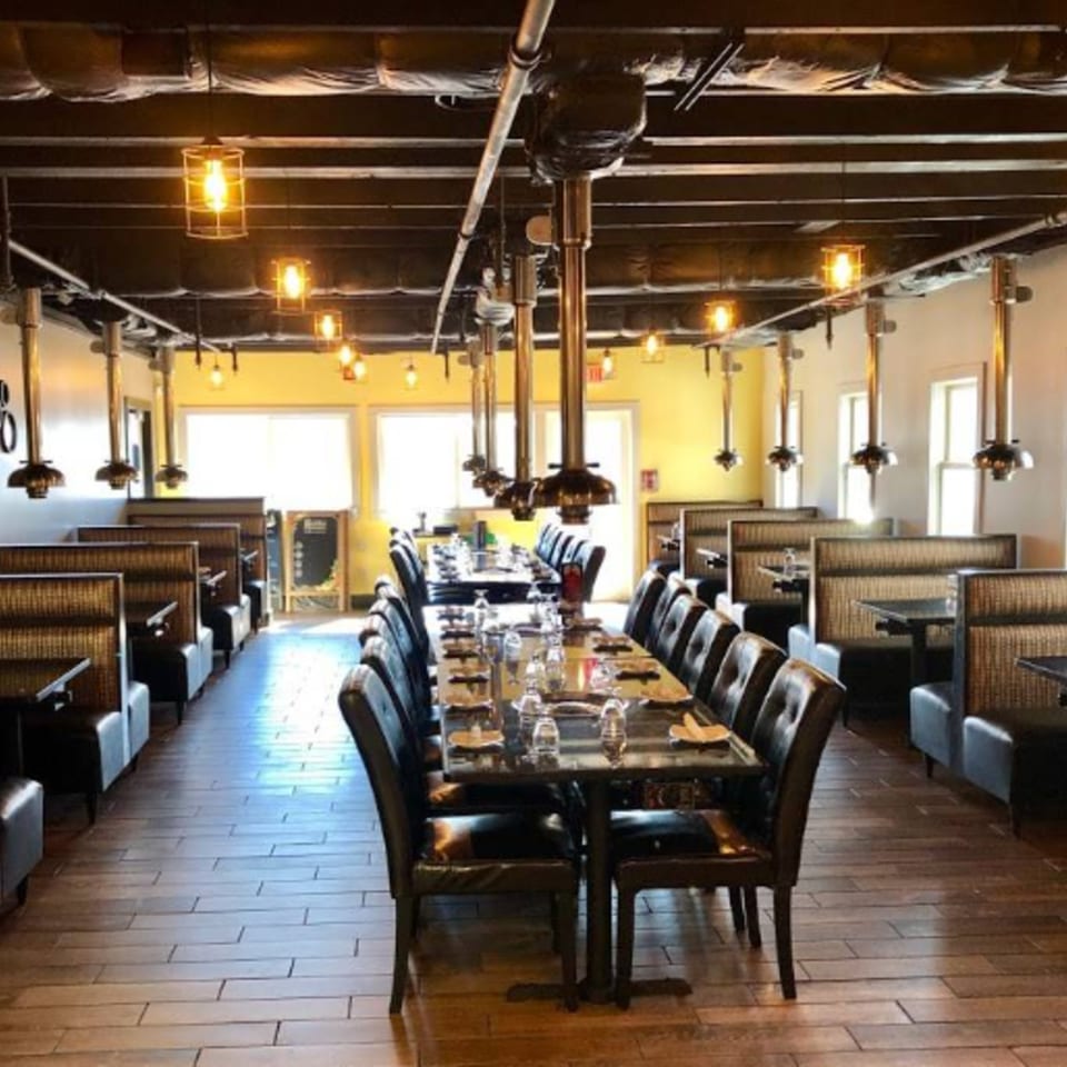 Bleu Ginger's dining room with long tables, booths, and industrial-style lighting fixtures.