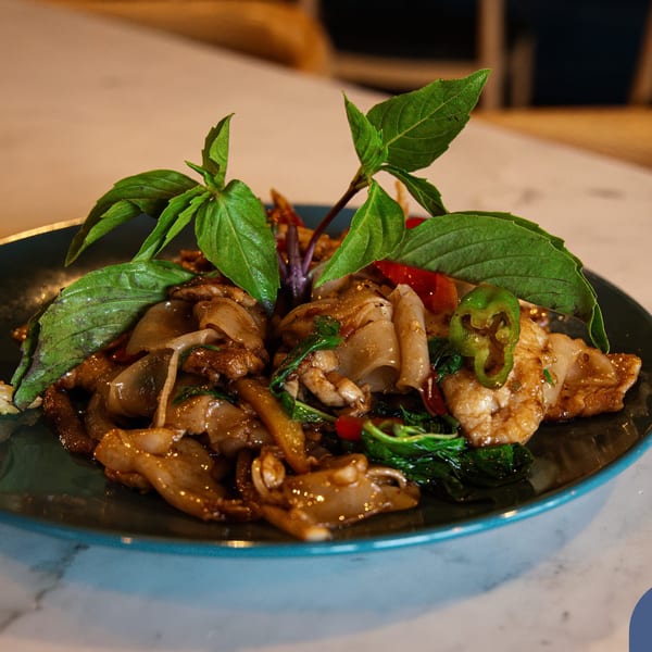 Bleu Ginger's Pad See Ew with wide noodles, chicken, basil, and chili on a blue plate.