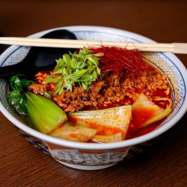 A vibrant bowl of Bleu Ginger's Asian-fusion ramen with minced meat, bok choy, and chili threads.